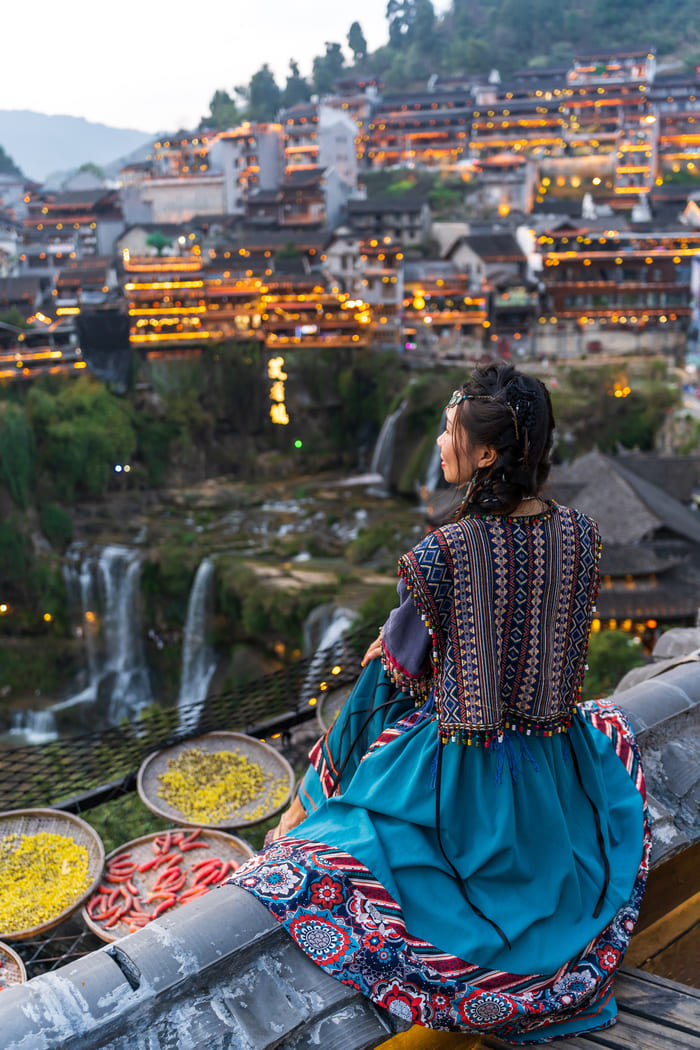Vista panorámica de la antigua ciudad de Lijiang al anochecer con cascadas y arquitectura tradicional china iluminada.